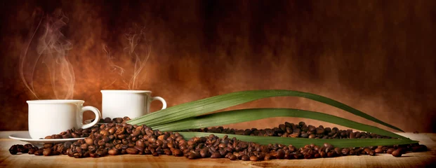 Foto auf Acrylglas Für die Küche Kaffee in der Tasse, mit Bohnen auf dem Tisch verstreut