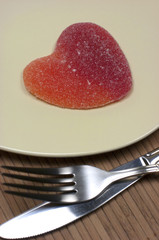 Corazón de golosina, plato y cubiertos.