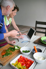Obraz na płótnie Canvas Couple looking at a recipe on-line