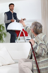 Young man putting up a light for an elderly woman