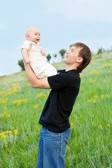 happy young man playing his baby boy on nature on slope