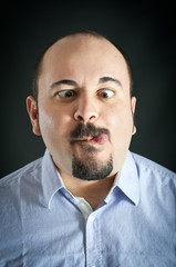 Man portrait with grimace expression on dark background.