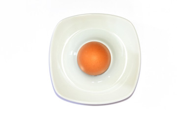 Brown egg in an egg cup in front of white background