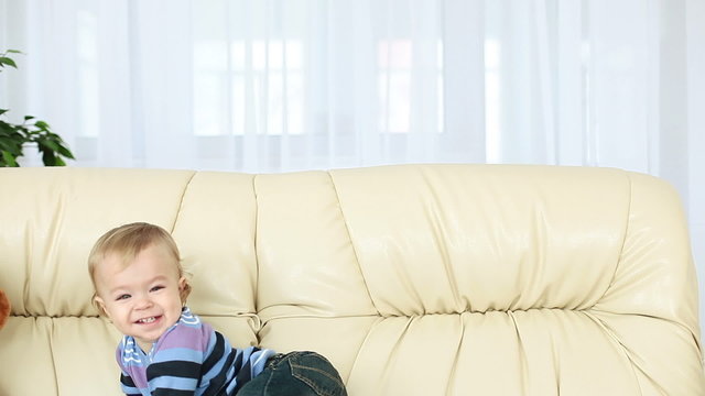 Smiling baby boy standing on the couch