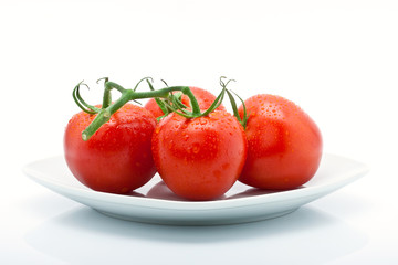 Tomaten mit Tropfen auf Teller isoliert vor weissem Hintergrund
