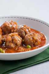 Stewed meatballs with peas, tomato and onion