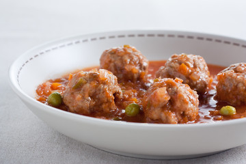 Stewed meatballs with peas, tomato and onion