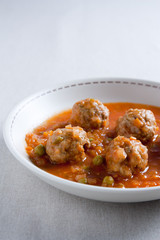 Stewed meatballs with peas, tomato and onion.