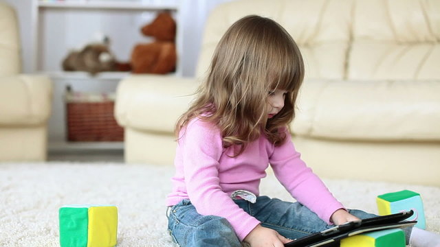 Baby girl with tablet PC  siting on the floor
