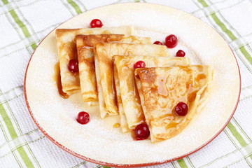 Pancakes with cranberry berries and honey on a plate