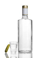 Bottle of vodka and wineglass with cucumber isolated on white