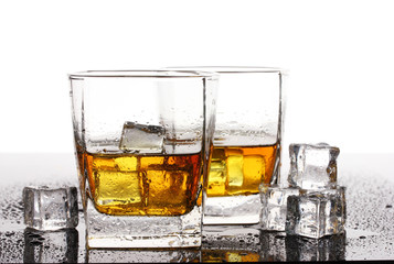 two glasses of scotch whiskey and ice on table isolated on white