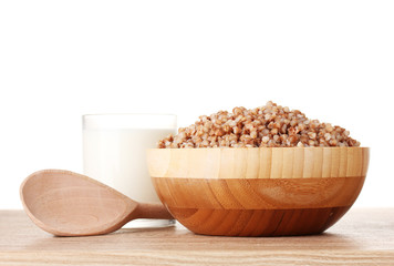 Boiled buckwheat in a wooden bowl with a glass of milk