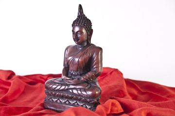 Side View of Wooden Buddha statue on Red Fabric