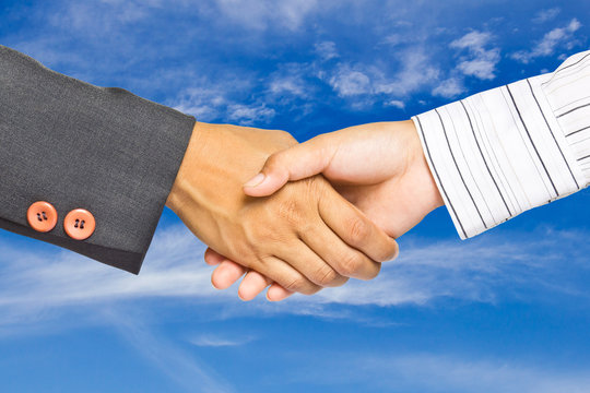 Business handshake on sky background