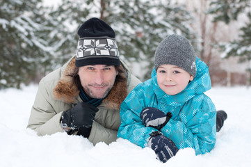 Fototapeta na wymiar Dad and son rest in the snow in the park