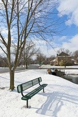 Winter city scene with a bench near pond  at neighborhood recrea