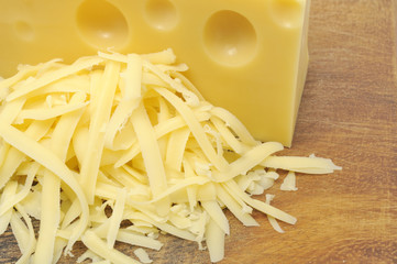Pile of Grated Cheese and Chunk of Cheese on Chopping Board