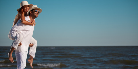 happy couple piggyback ride on sea shore