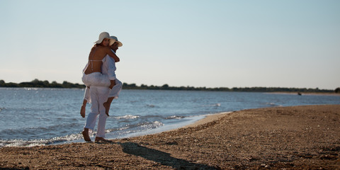 happy couple piggyback ride on sea shore