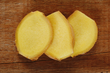 Sliced ginger root on wood background