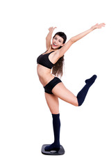 Fototapeta premium Happy beautiful young woman dancing over a weight scale.