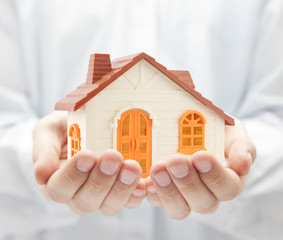 Small orange toy house in hands