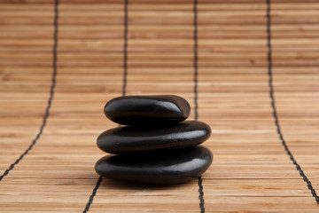 Fototapeta na wymiar Spa Stones. black shiny zen stones with water drops over black b