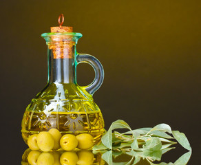 olive oil in jar and olives on yellow background