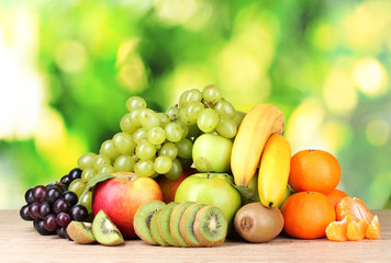 Ripe juicy fruits on wooden table on green background