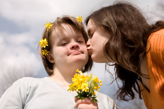 A girl kissing her sister with Down syndrome.