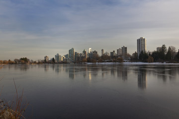 Fototapeta na wymiar Vancouver, BC skyline reflects over frozen lost lagoon