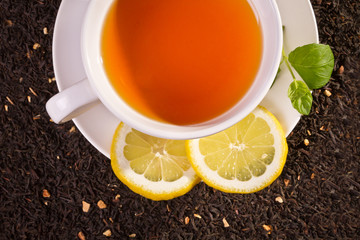 Lemon tea and fresh leaves on grain background