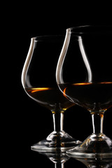 Two glasses of cognac on black background