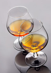 Two glasses of cognac on grey background