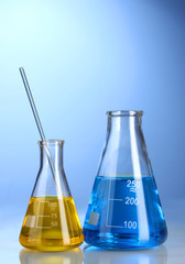 Two flasks with yellow and blue liquid with reflection