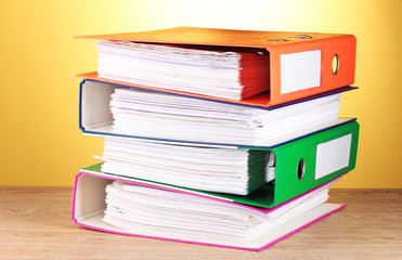 bright office folders on wooden table on yellow background.