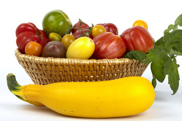 Korb mit vielen bunten Bio-Tomaten und zwei gelben Zucchinis