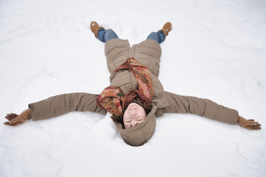 Winter fun - snow angel - happy woman playing in snow