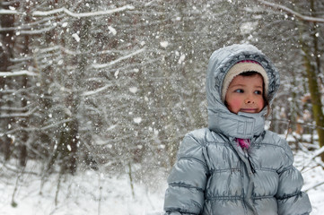 Fototapeta na wymiar Happy child having fun in winter forest. Little girl