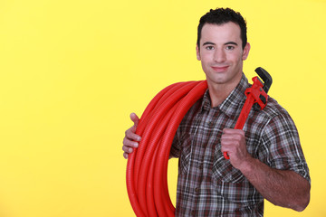 Tradesman holding corrugated tubing and a pipe wrench