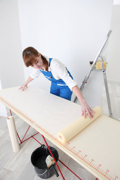 Woman laying wallpaper out on a pasting table