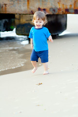 Little boy running on the beach of sea