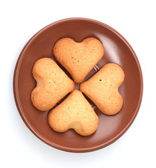 Four leaf clover biscuit on brown saucer isolated on white