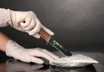 packets of Cocaine opening with a knife on grey background