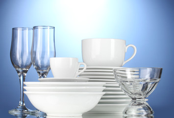 Fototapeta premium empty bowls, plates, cups and glasses on blue background