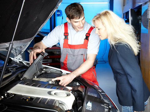 Motor mechanic shows his customer the details of an engine bay