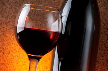 Wineglass with red wine and bottle, close-up