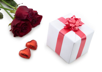 A bouquet of roses and a romantic gift on white background.