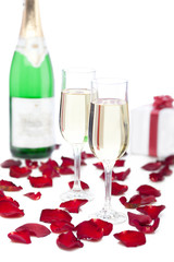 Fototapeta na wymiar Two glasses of champagne, gift box, rose petals on white backgro
